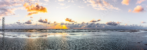 Schöner Sonnenuntergang am Meer mit Wolken und Wasserspiegelung