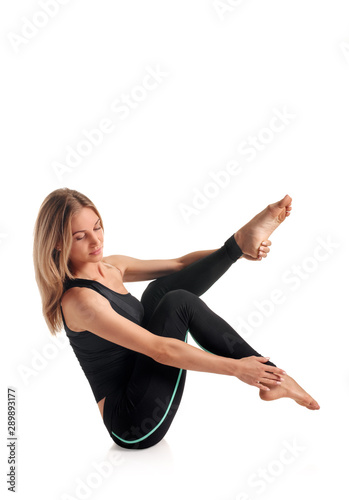 Young healthy woman in black sportswear doing pilates exercise
