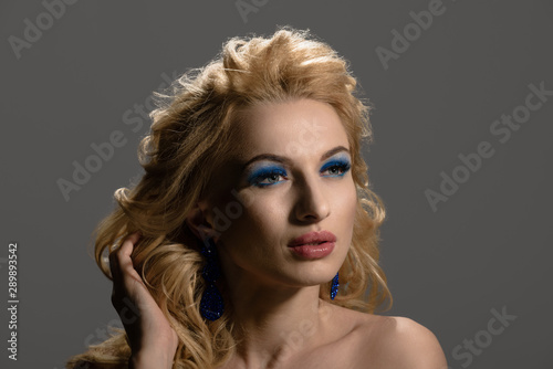 Beautiful female model with elegant hairstyle and blue earrings