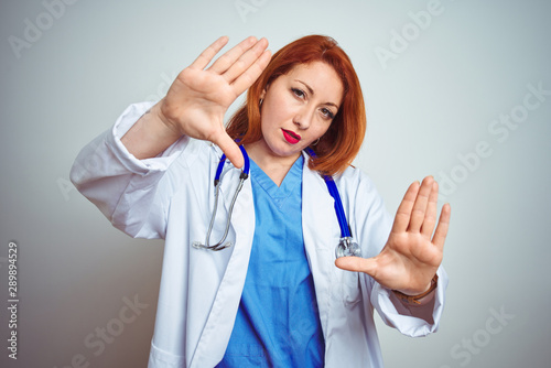 Young redhead doctor woman using stethoscope over white isolated background doing frame using hands palms and fingers  camera perspective