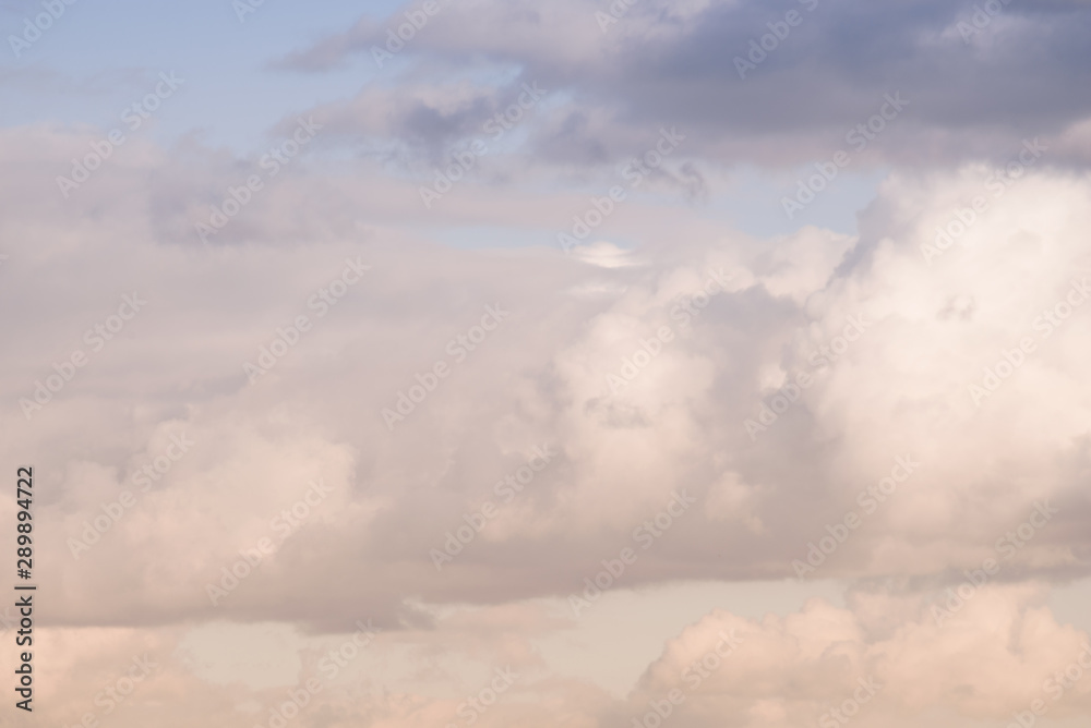 The clouds. The light of the sun through the clouds against a bright sky at sunset. Clouds on the blue sky. Sunset. The clouds. The light of the sun through the clouds against a bright sky at sunset. Clouds on the blue sky. Sunset.