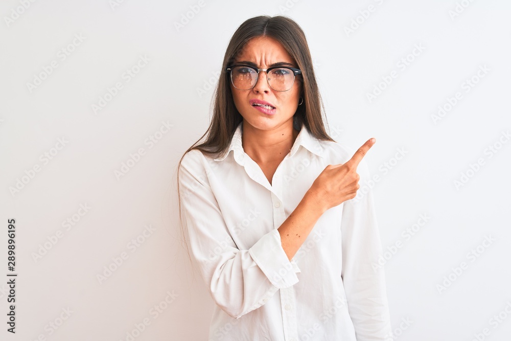 Young beautiful businesswoman wearing glasses standing over isolated white background Pointing aside worried and nervous with forefinger, concerned and surprised expression Young beautiful businesswoman wearing glasses standing over isolated white background Pointing aside worried and nervous with forefinger, concerned and surprised expression
