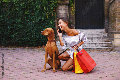 Young woman shopping with her dog talking on the phone