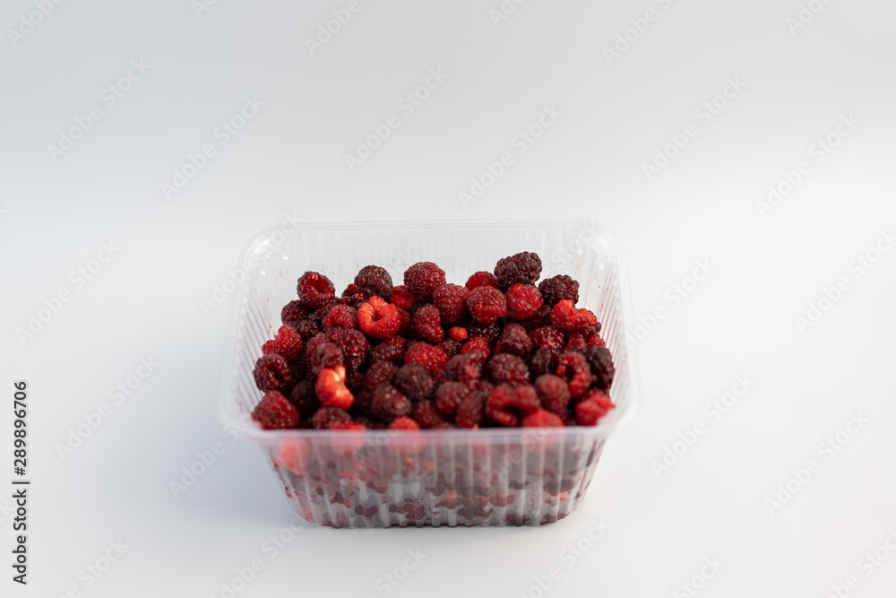 A lot of fresh raspberries in plastic packaging on a white background A lot of fresh raspberries in plastic packaging on a white background
