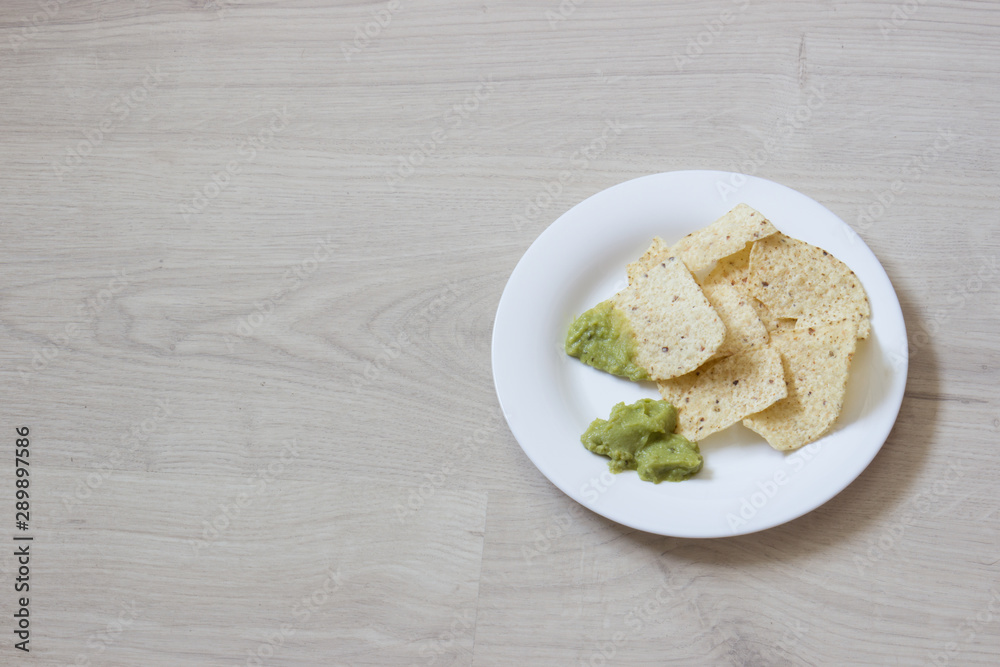 nachos on a white plate ready to eat with guacamole nachos on a white plate ready to eat with guacamole