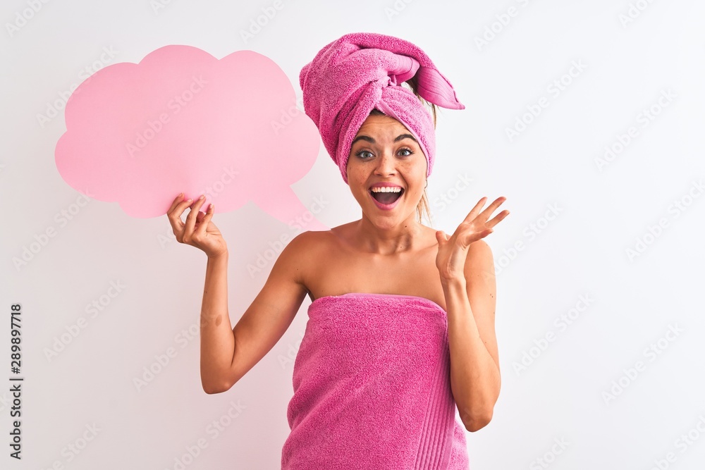 Beautiful woman wearing shower towel holding speech bubble over isolated white background very happy and excited, winner expression celebrating victory screaming with big smile and raised hands Beautiful woman wearing shower towel holding speech bubble over isolated white background very happy and excited, winner expression celebrating victory screaming with big smile and raised hands