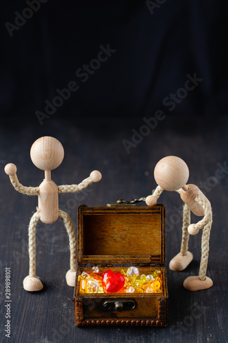 Two figurines standing beside a little treasure chest, filled with sparkling jewellry