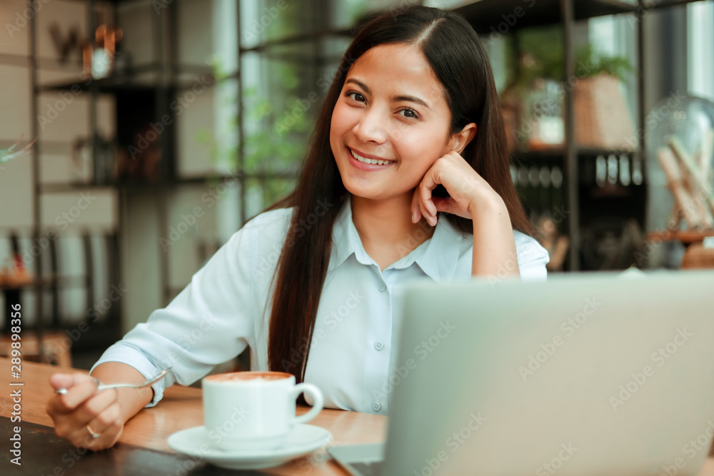 Asian woman in blue shirt working and drink coffee in coffee shop cafe vintage color tone Asian woman in blue shirt working and drink coffee in coffee shop cafe vintage color tone