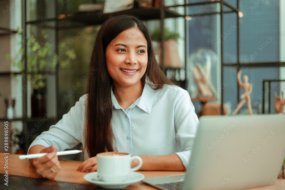 Asian woman in blue shirt working and drink coffee in coffee shop cafe vintage color tone Asian woman in blue shirt working and drink coffee in coffee shop cafe vintage color tone