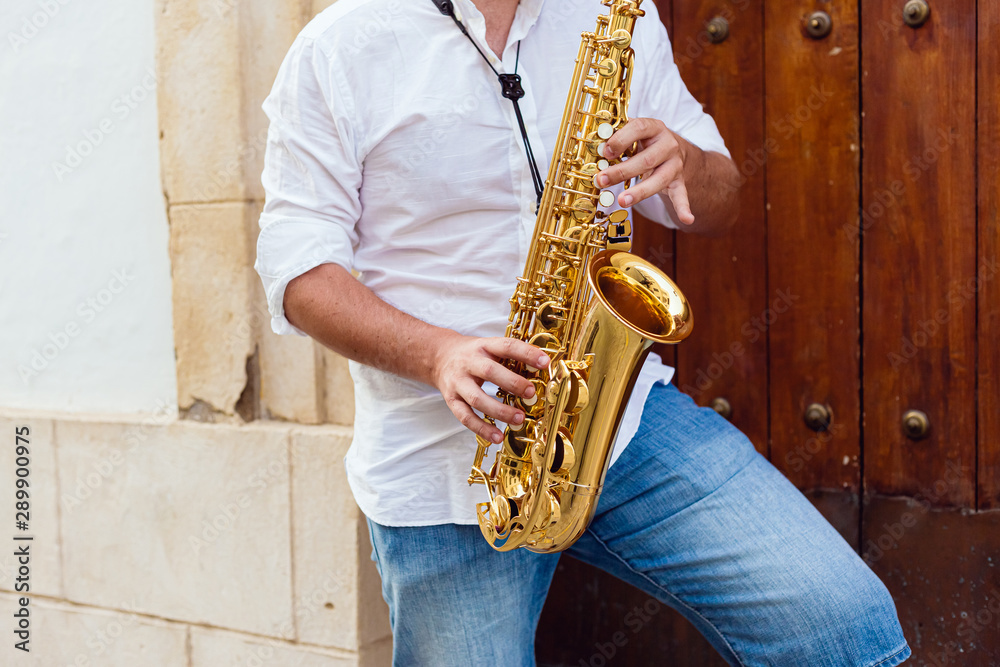 Close up of a man playing passionately his saxophone at the door of a building on the street