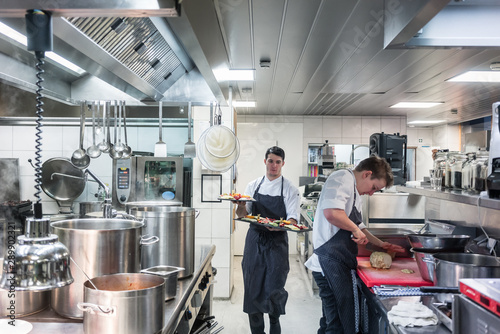 Two chefs preparing and serving high quality food while working in the kitchen of a restaurant photo