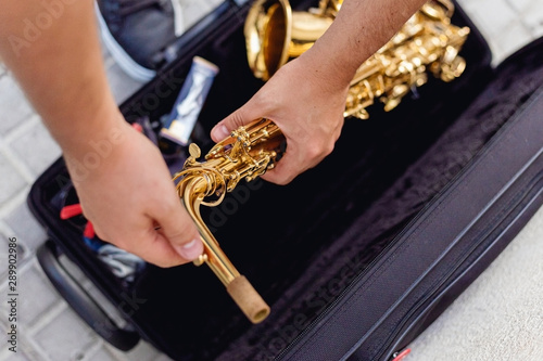 Close up of a man keeping his saxophone on a case on the street