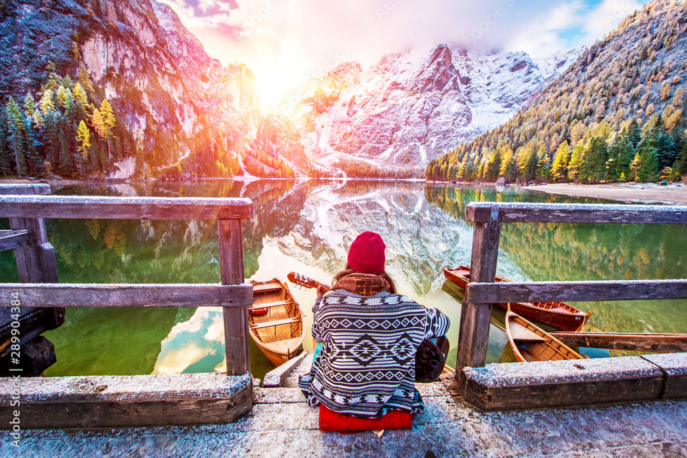 Amazing fascinating magical autumn winter landscape with a girl playing guitar over a lake on Fanes-Sennes-Braies in the Dolomites Alps. (meditation, relaxation, stress relief, harmony - concept)