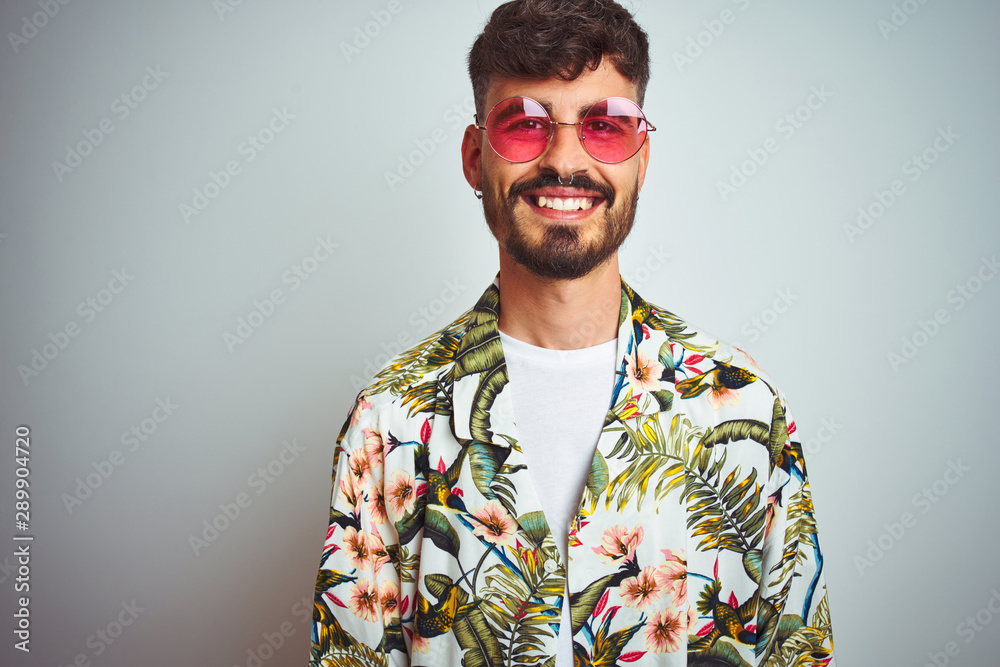 Man with tattoo on vacation wearing summer shirt sunglasses over isolated white background with a happy and cool smile on face. Lucky person. Man with tattoo on vacation wearing summer shirt sunglasses over isolated white background with a happy and cool smile on face. Lucky person.