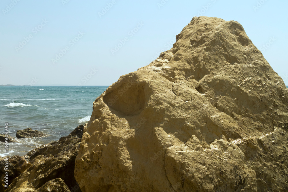 Yellow rock in front of blue sea and sky