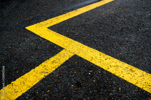 Vivid yellow lines on black surface, road signage abstract elements. © Daguimagery