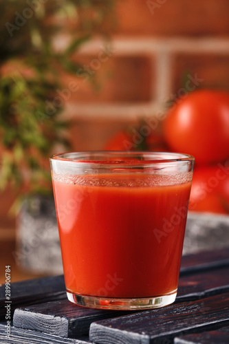 Tasty Tomato juice in a glass with ripe red tomatoes.