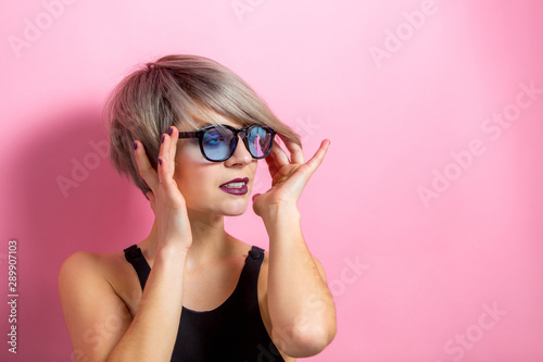 Fashion beautiful young woman with short hair and sunglasses over pink background photo
