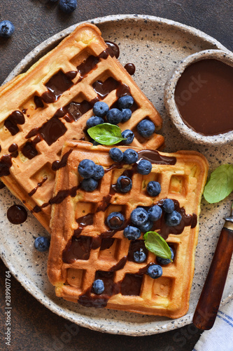 Belgian waffles for breakfast with chocolate sauce and blueberries.