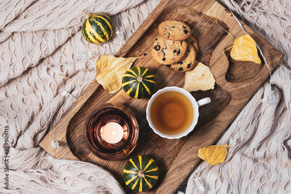 Cozy autumn evening at home with cup of aromatic herbal tea, homemade cookies with chocolate pieces, candle and warm blanket. Hygge home interior. Lagom concept. Cozy autumn evening at home with cup of aromatic herbal tea, homemade cookies with chocolate pieces, candle and warm blanket. Hygge home interior. Lagom concept.