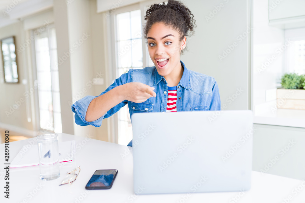 Young african american student woman using computer laptop very happy pointing with hand and finger