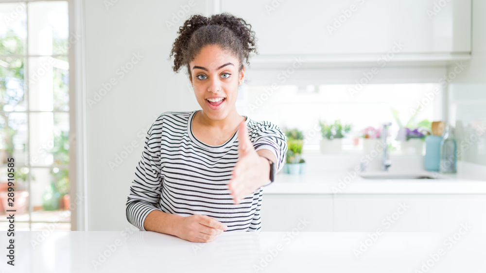 Beautiful african american woman with afro hair wearing casual striped sweater smiling friendly offering handshake as greeting and welcoming. Successful business. Beautiful african american woman with afro hair wearing casual striped sweater smiling friendly offering handshake as greeting and welcoming. Successful business.