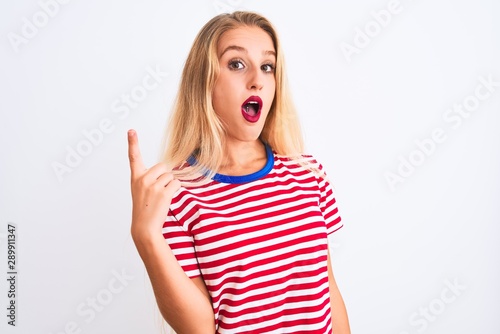 Young beautiful woman wearing red striped t-shirt standing over isolated white background pointing finger up with successful idea. Exited and happy. Number one.