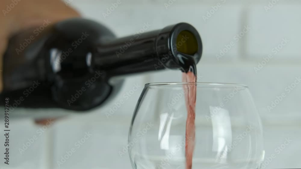 Wine is poured into a glass close-up. Wine is poured into a glass close-up.
