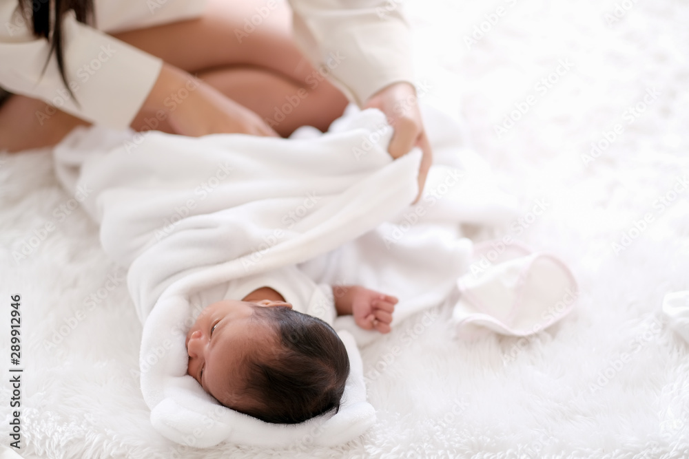 Newborn baby was swaddling with white cloth by her mother and the activity is on bed. - obrazy, fototapety, plakaty 