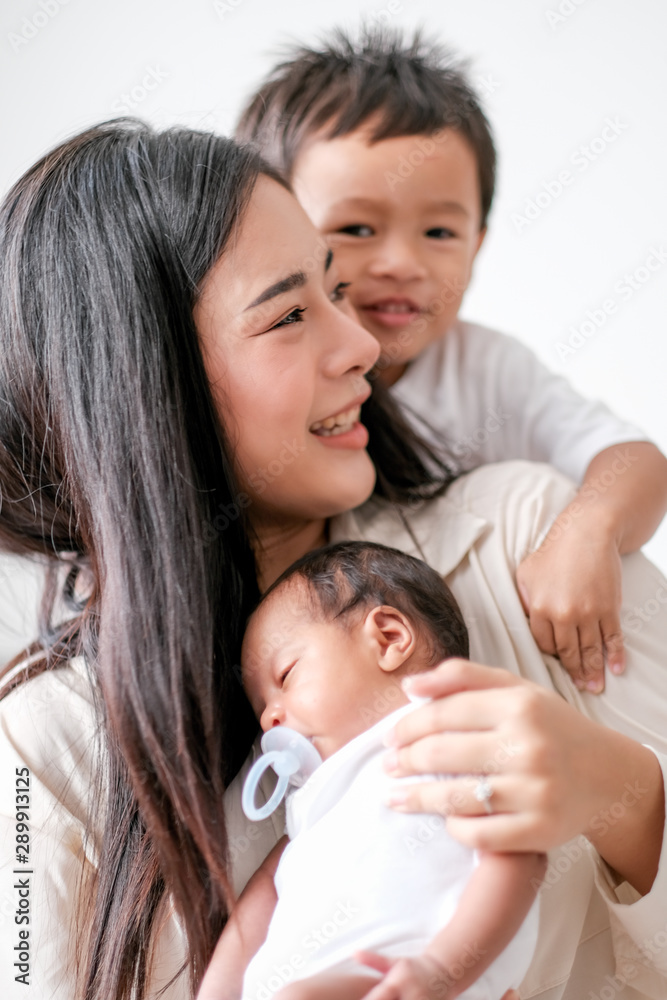 Soft blur image of beautiful Asian mother have fun with her little boy and newborn baby in front of day light. Soft blur image of beautiful Asian mother have fun with her little boy and newborn baby in front of day light.