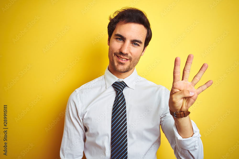 Young handsome businessman wearing elegant shirt and tie over isolated yellow background showing and pointing up with fingers number four while smiling confident and happy. Young handsome businessman wearing elegant shirt and tie over isolated yellow background showing and pointing up with fingers number four while smiling confident and happy.