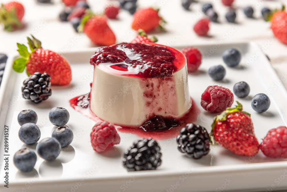 Delicious italian dessert panna cotta with berry sauce, fresh berries on white wooden background Delicious italian dessert panna cotta with berry sauce, fresh berries on white wooden background