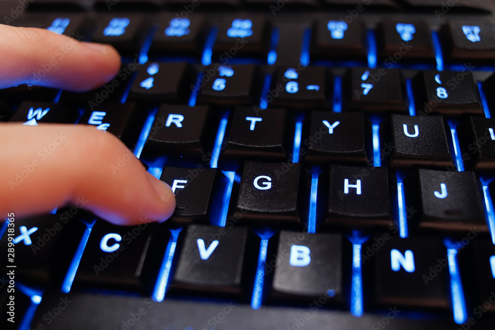 Finger over backlighted keyboard pressing the F character. Popular internet concept that stands for paying respects to someone. Finger over backlighted keyboard pressing the F character. Popular internet concept that stands for paying respects to someone.