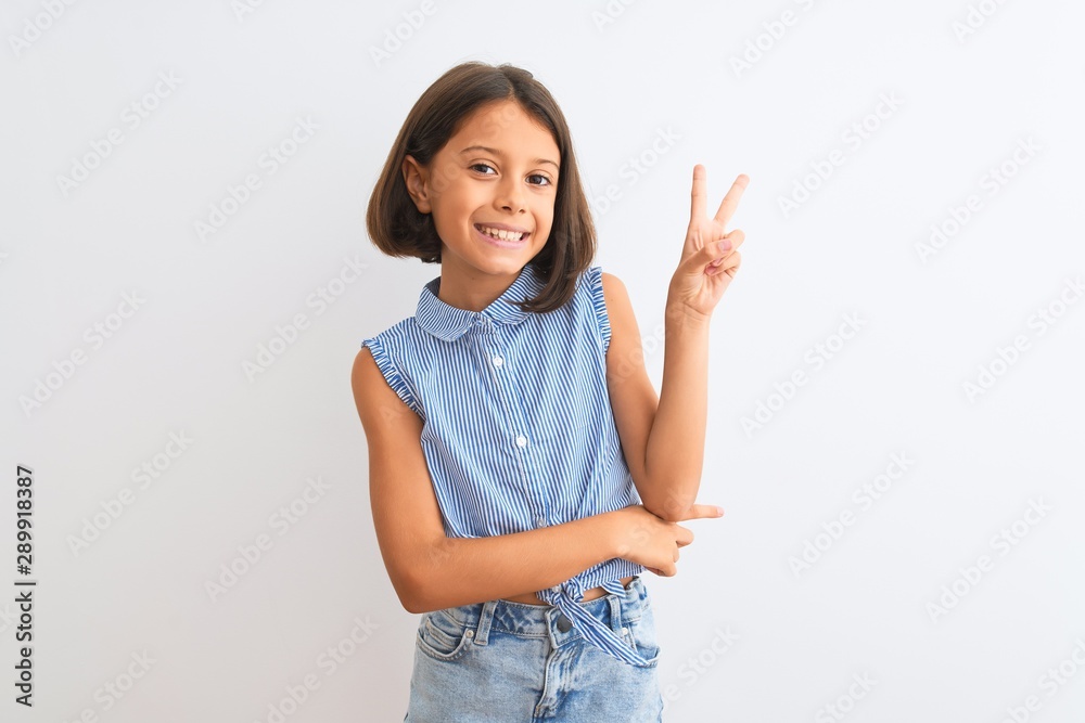 Young beautiful child girl wearing blue casual shirt standing over isolated white background smiling with happy face winking at the camera doing victory sign. Number two. Young beautiful child girl wearing blue casual shirt standing over isolated white background smiling with happy face winking at the camera doing victory sign. Number two.