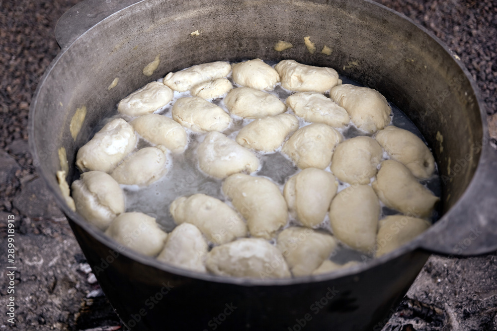 National Ukrainian food. Dumplings are boiling in a large cauldron at the stake. National Ukrainian food. Dumplings are boiling in a large cauldron at the stake.