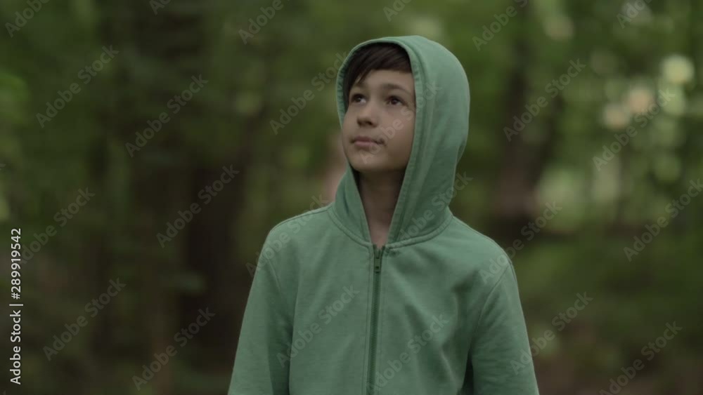 Funny boy in the hood walks through the forest, enjoys weather, sun light Funny boy in the hood walks through the forest, enjoys weather, sun light