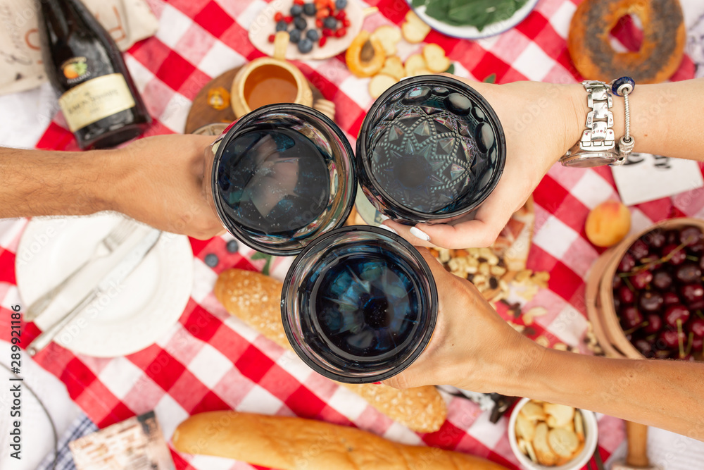 Summer picnic holidays. Top view friends clink glasses on checkered blanket background. Instagram content.