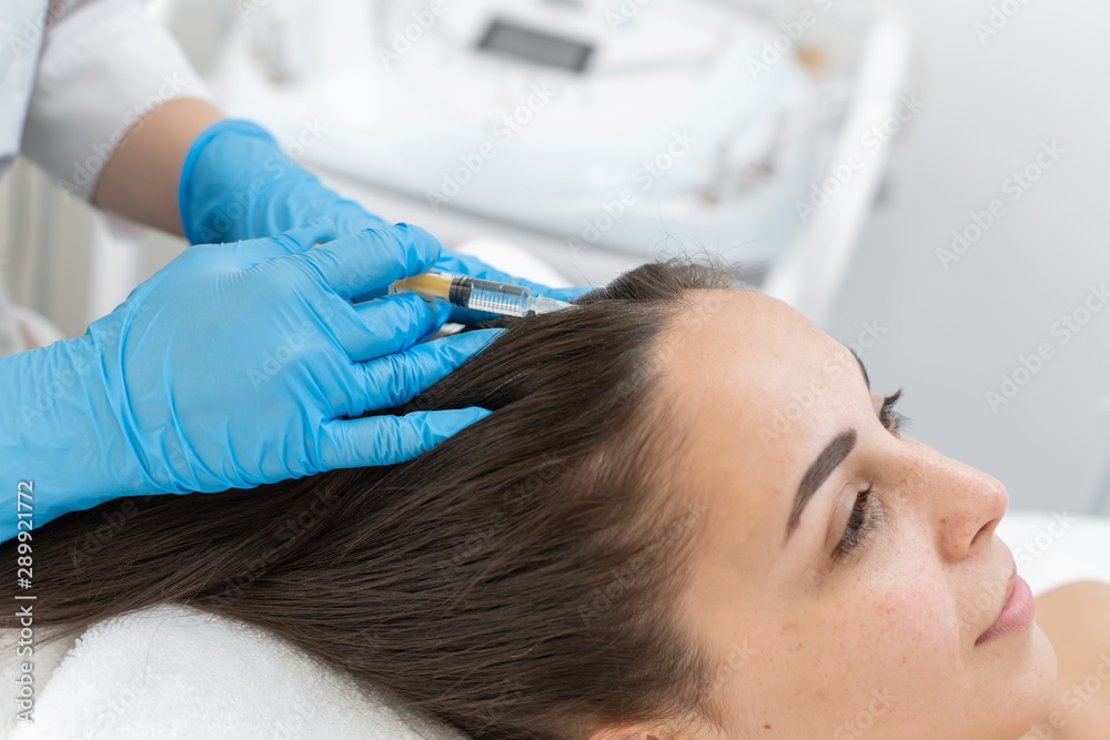 Beautician injections for healthy hair growth. Mesotherapy of the scalp. A young girl is undergoing a course of spa treatments in the office of a beautician. Moisturizing