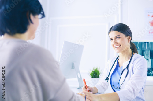 Female doctor calming down a patient at a hospital consulting room, holding her hand