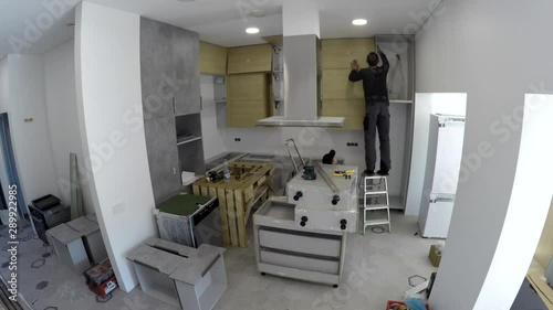 Skilled workers installing kitchen furniture and home appliances. Timelapse