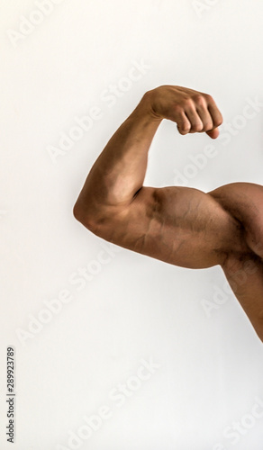 Bodybuilder flexing his muscles in studio. The torso of attractive male body builder on white background.