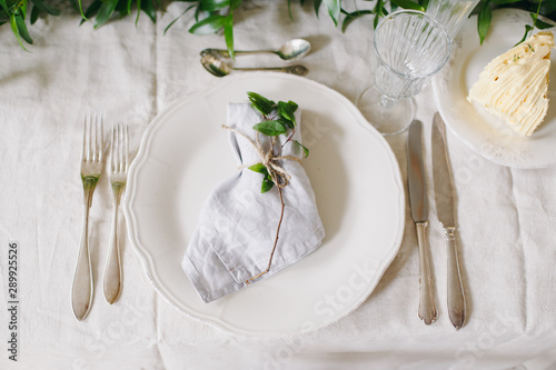 Wedding table. Two spoons two knife two forks. Plate with decor. Wedding cake. Wedding table setting.