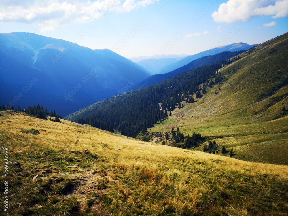 Alpine landscape with green mountains and blue sky covered with white clouds.   Fagaras - trail to the Lespezi Peak