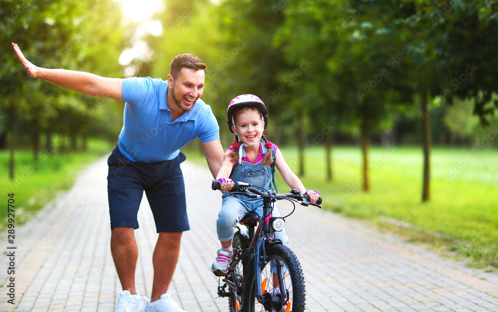 happy family father teaches child daughter to ride a bike in the Park