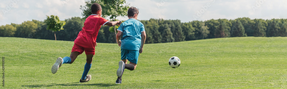 panoramic shot of african american kid playing football with friend panoramic shot of african american kid playing football with friend