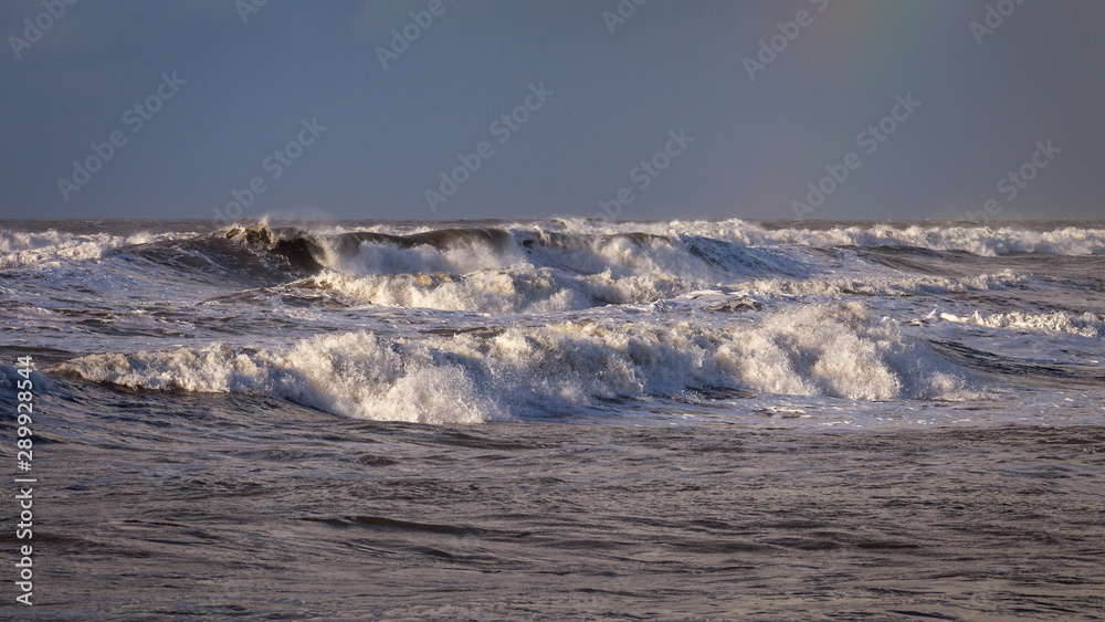 Stormy sea at Westward Ho in North Devon with rainbow in the distance