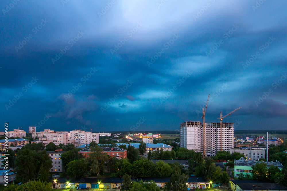 Industrial landscape with silhouettes of cranes on the thunderclouds background Industrial landscape with silhouettes of cranes on the thunderclouds background