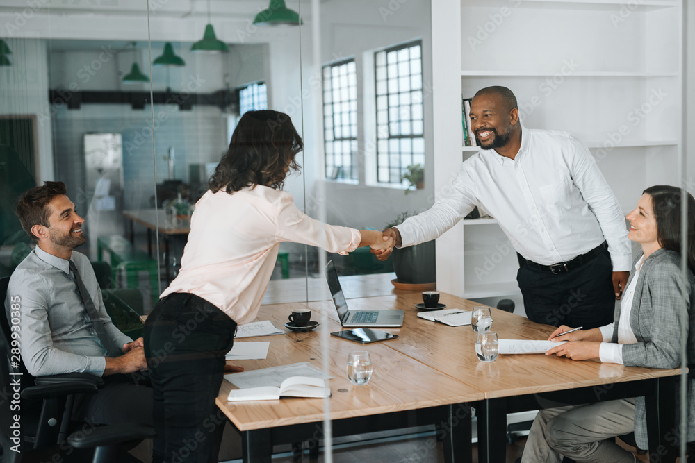 Smiling businessspeople standing in a boardroom shaking hands together