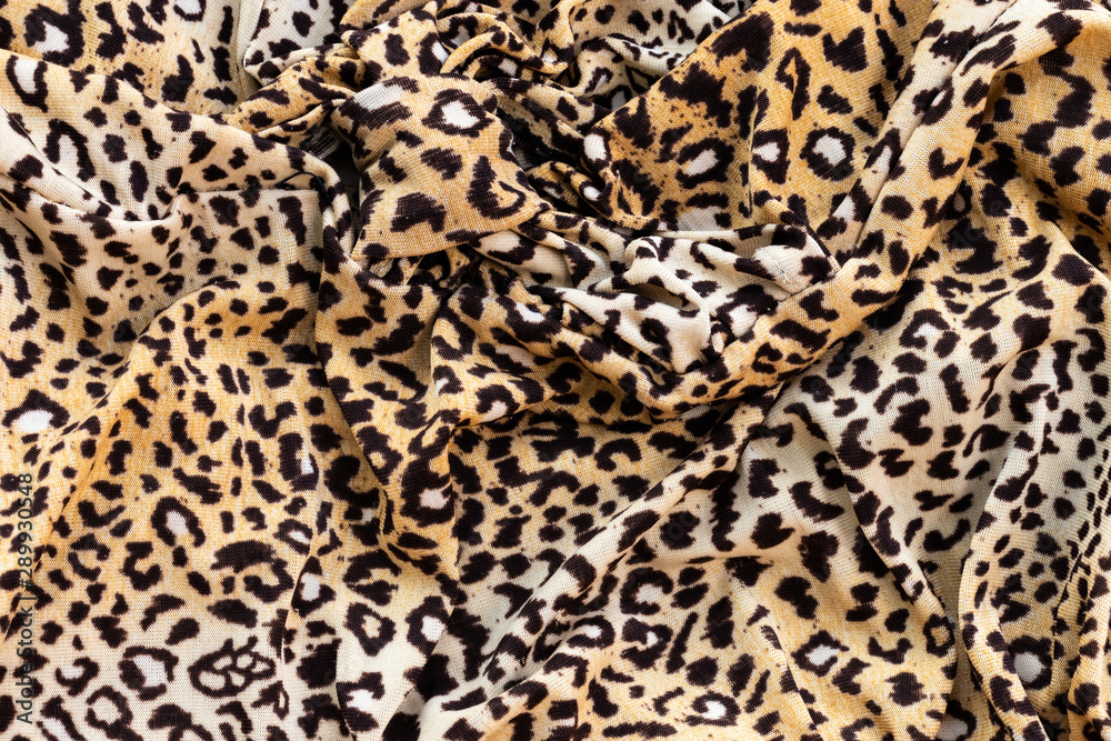 Background in the form of a knitwear product with a pattern similar to a leopard skin in cream brown with crumpled fabric