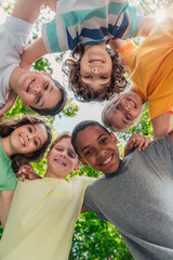 bottom view of cheerful multicultural children looking at camera in park